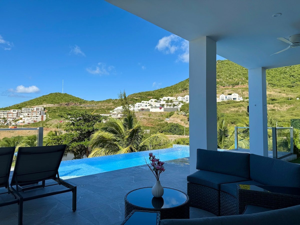 Infinity-pool terrace with neighbouring Indigo Bay villas visible on the hillside, St. Maarten